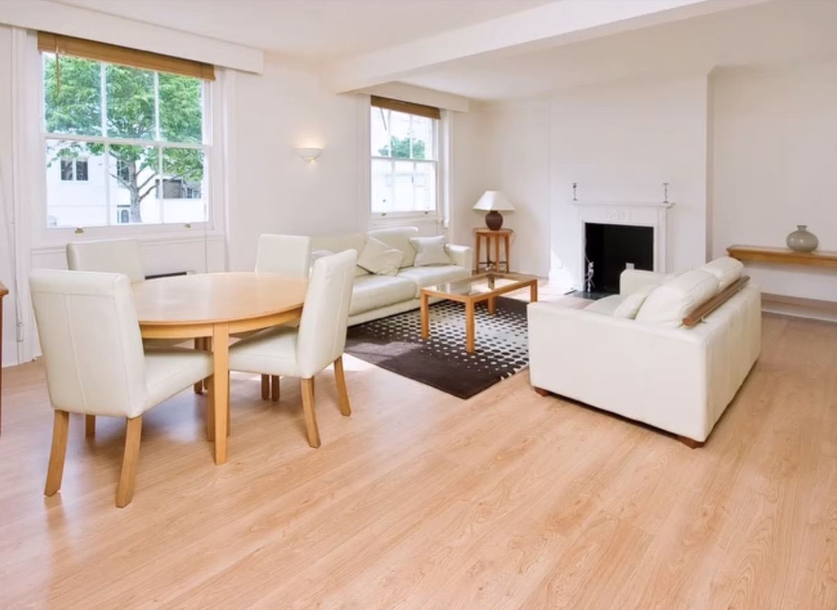 The living room before: cream sofas, a round dining table and a laminate floor