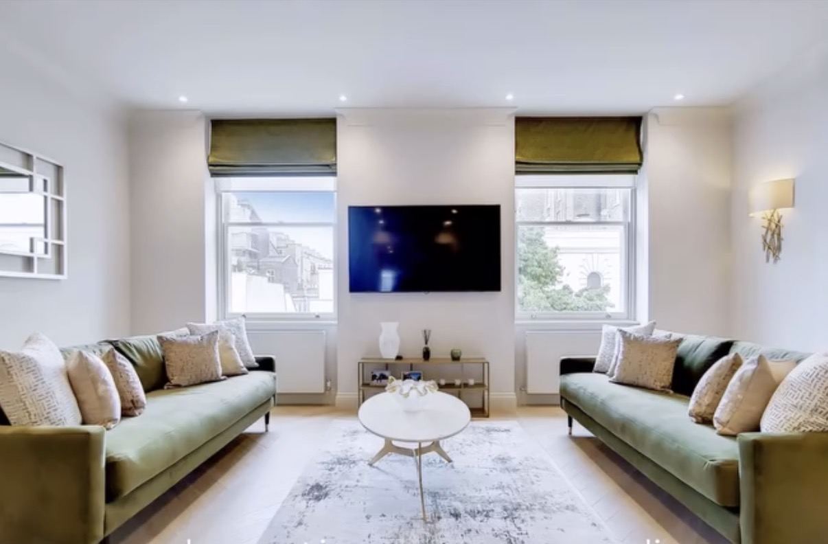 The living room after: green velvet sofas, oval coffee table, Roman blinds