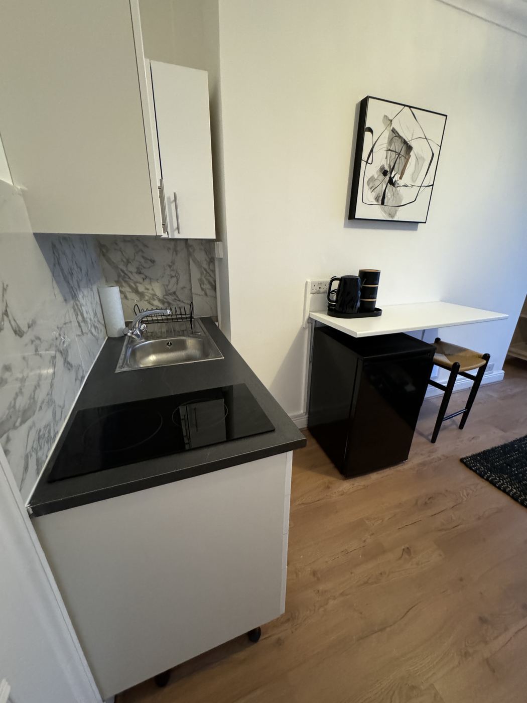 Kitchenette with marble-effect splashback and black worktop